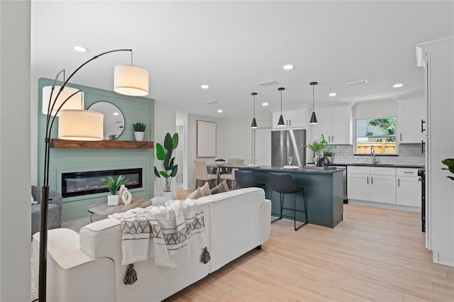 1707 Solon Ave, Dunedin, FL 34698 - living area featuring light wood finished floors, a glass covered fireplace, and recessed lighting