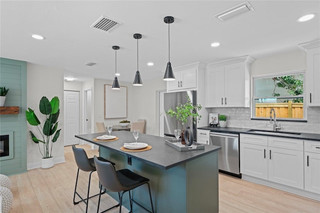 1707 Solon Ave, Dunedin, FL 34698 - kitchen with dishwasher, dark countertops, a breakfast bar, white cabinetry, and light wood-type flooring