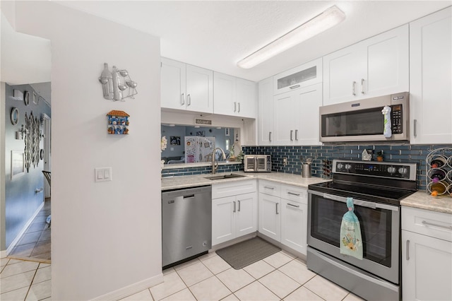 5725 Pelican Pointe Dr Unit 1, Sebastian, FL 32958 - kitchen featuring stainless steel appliances, light tile patterned floors, decorative backsplash, and white cabinetry