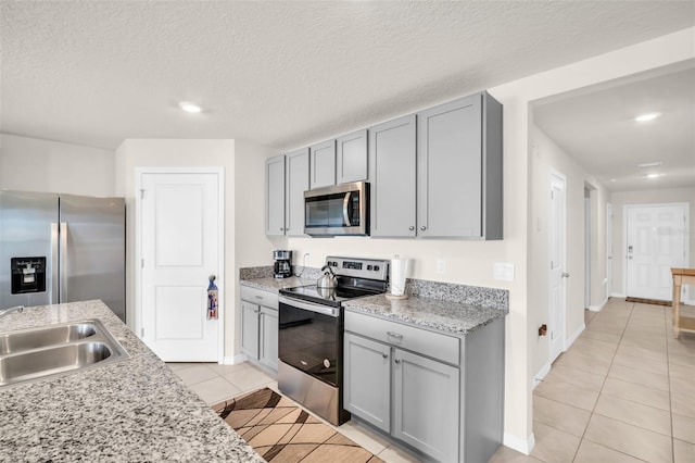 7774 Sail Clover Ln, Zephyrhills, FL 33540 - kitchen with appliances with stainless steel finishes, gray cabinets, light tile patterned flooring, recessed lighting, and a textured ceiling