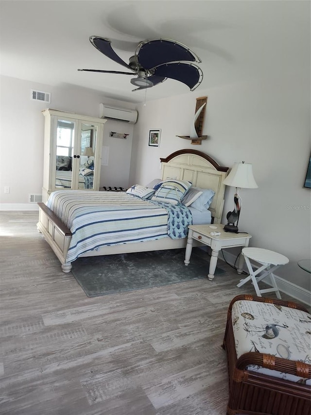 1626 Sea Breeze Dr, Tarpon Springs, FL 34689 - bedroom with an AC wall unit, french doors, wood finished floors, and a ceiling fan