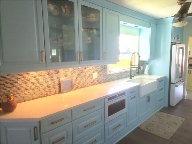 1626 Sea Breeze Dr, Tarpon Springs, FL 34689 - kitchen featuring white refrigerator with ice dispenser, tasteful backsplash, light countertops, and glass insert cabinets