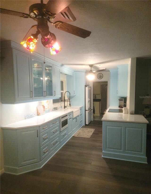 1626 Sea Breeze Dr, Tarpon Springs, FL 34689 - kitchen featuring freestanding refrigerator, ceiling fan, dark wood-style flooring, glass insert cabinets, and light countertops