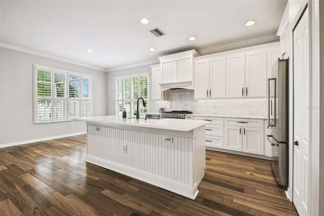 18203 Tivoli Ln, Lutz, FL 33558 - kitchen with high end fridge, ornamental molding, backsplash, white cabinets, and a kitchen island with sink