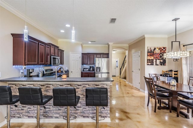 1031 Andrew Aviles Cir, Tampa, FL 33619 - kitchen featuring stainless steel appliances, a peninsula, finished concrete floors, arched walkways, and decorative light fixtures