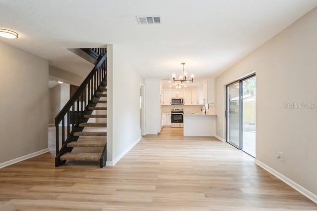 14909 Oldgate Pl, Tampa, FL 33624 - kitchen with stainless steel microwave, stove, white cabinets, and light wood-style floors