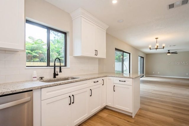 14909 Oldgate Pl, Tampa, FL 33624 - kitchen with dishwasher, light wood-type flooring, decorative backsplash, white cabinetry, and a chandelier