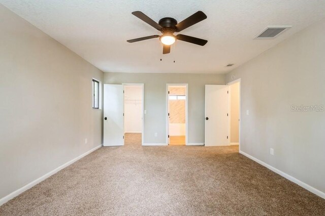 14909 Oldgate Pl, Tampa, FL 33624 - unfurnished bedroom with carpet, a spacious closet, connected bathroom, a ceiling fan, and a closet