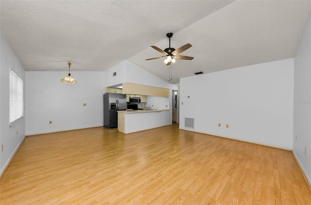 1902 Elaine Dr, Clearwater, FL 33760 - unfurnished living room featuring vaulted ceiling, light wood-style floors, ceiling fan, and a textured ceiling