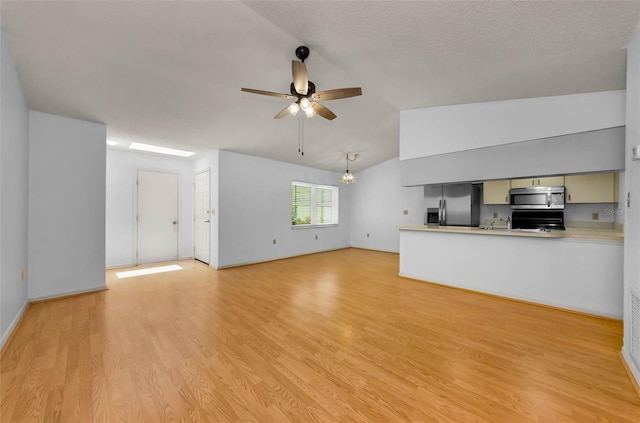 1902 Elaine Dr, Clearwater, FL 33760 - unfurnished living room featuring ceiling fan, vaulted ceiling, light wood finished floors, and a chandelier