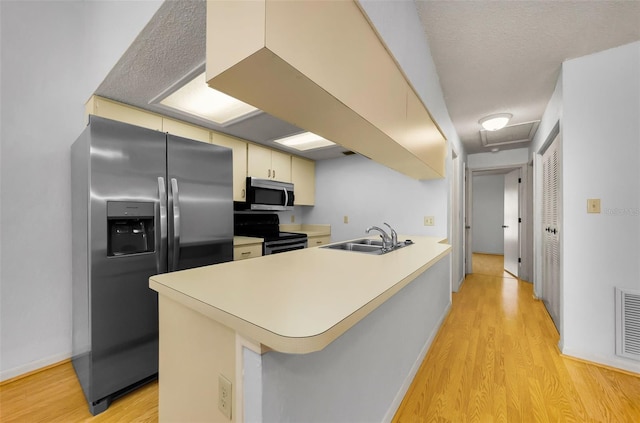 1902 Elaine Dr, Clearwater, FL 33760 - kitchen with stainless steel appliances, a peninsula, light wood-style flooring, and cream cabinetry