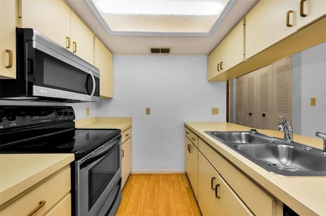 1902 Elaine Dr, Clearwater, FL 33760 - kitchen with stainless steel appliances, light wood-style flooring, light countertops, and cream cabinets