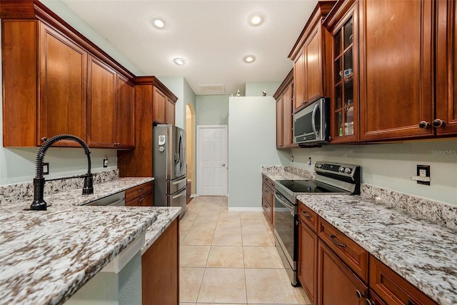 11220 Paradise Pointe Way, New Port Richey, FL 34654 - kitchen with stainless steel appliances, light stone counters, glass insert cabinets, light tile patterned floors, and recessed lighting