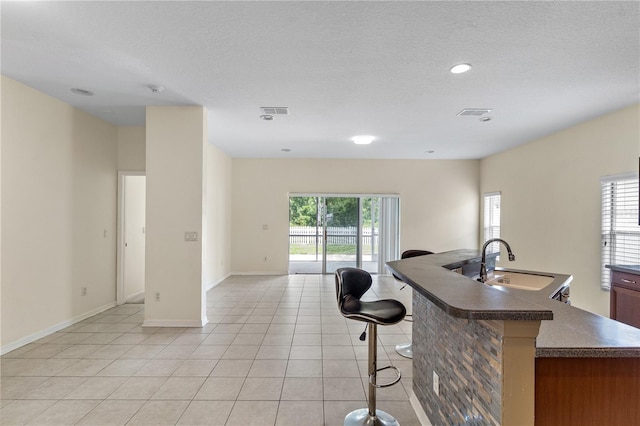 12631 Chenwood Ave, Hudson, FL 34669 - kitchen featuring dark countertops, open floor plan, a breakfast bar, light tile patterned floors, and a textured ceiling