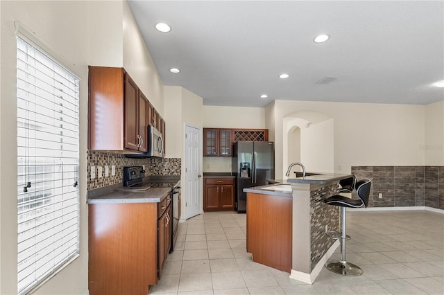 12631 Chenwood Ave, Hudson, FL 34669 - kitchen featuring stainless steel appliances, a kitchen breakfast bar, light tile patterned flooring, glass insert cabinets, and recessed lighting