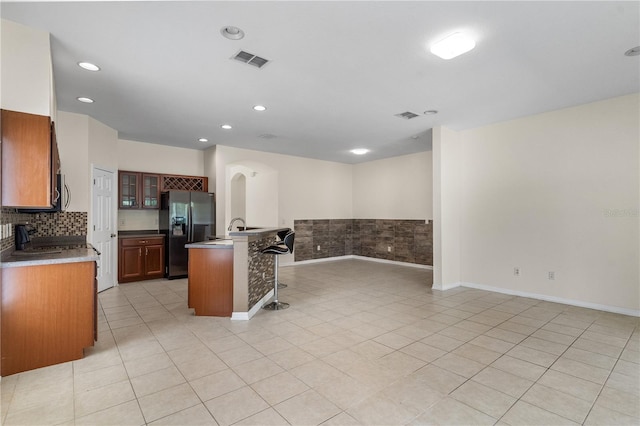 12631 Chenwood Ave, Hudson, FL 34669 - kitchen featuring refrigerator with ice dispenser, a breakfast bar, glass insert cabinets, light tile patterned flooring, and recessed lighting