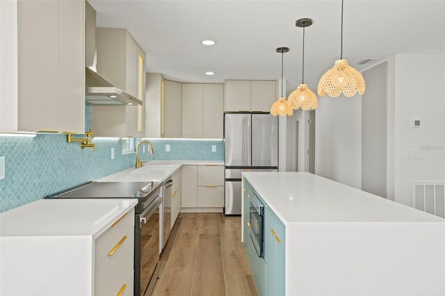 4704 W Fairview Hts, Tampa, FL 33616 - kitchen featuring stainless steel appliances, wall chimney range hood, light wood-type flooring, a center island, and light countertops