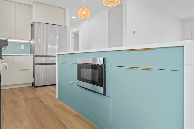 4704 W Fairview Hts, Tampa, FL 33616 - kitchen with appliances with stainless steel finishes, light wood finished floors, hanging light fixtures, recessed lighting, and decorative backsplash