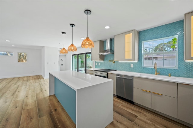 4704 W Fairview Hts, Tampa, FL 33616 - kitchen featuring wall chimney range hood, stainless steel appliances, a kitchen island, light wood-style floors, and light countertops