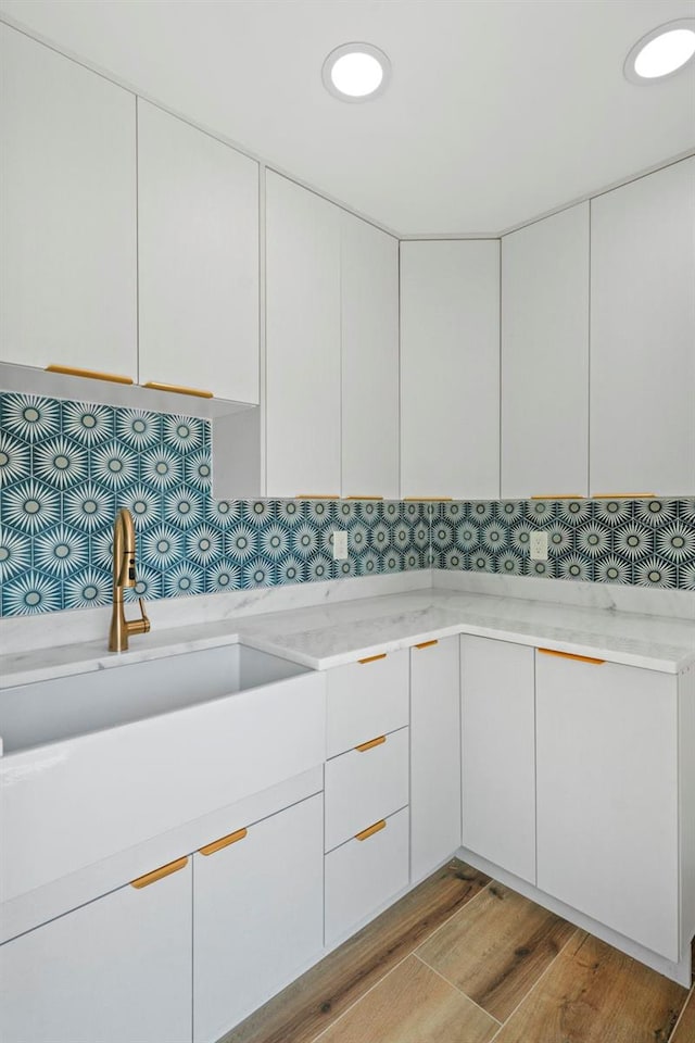 4704 W Fairview Hts, Tampa, FL 33616 - kitchen with light wood-type flooring, white cabinets, and light stone counters