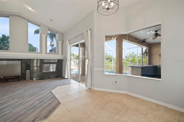10101 Paddock Oaks Dr, Riverview, FL 33569 - tiled entryway featuring vaulted ceiling, a chandelier, a glass covered fireplace, and a ceiling fan