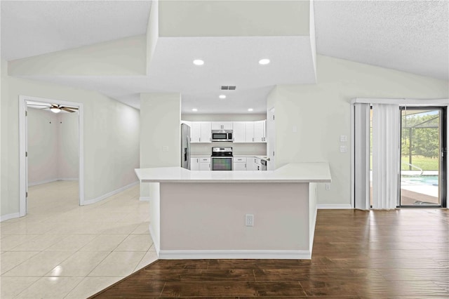 2141 Coachman Rd, Spring Hill, FL 34608 - kitchen with stainless steel appliances, lofted ceiling, light countertops, white cabinetry, and a peninsula