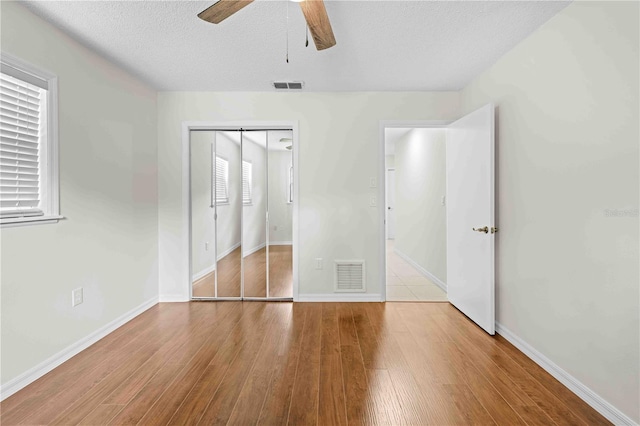 2141 Coachman Rd, Spring Hill, FL 34608 - unfurnished bedroom featuring wood finished floors, ceiling fan, a textured ceiling, and a closet