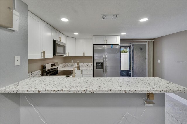 6601 121st Ave Unit I, Largo, FL 33773 - kitchen featuring appliances with stainless steel finishes, a peninsula, white cabinetry, recessed lighting, and a breakfast bar