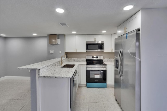 6601 121st Ave Unit I, Largo, FL 33773 - kitchen featuring stainless steel appliances, light tile patterned flooring, a peninsula, white cabinetry, and recessed lighting