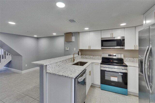 6601 121st Ave Unit I, Largo, FL 33773 - kitchen with stainless steel appliances, a peninsula, light tile patterned flooring, white cabinetry, and recessed lighting
