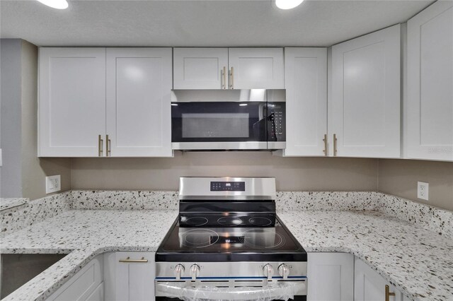 6601 121st Ave Unit I, Largo, FL 33773 - kitchen with stainless steel appliances, white cabinetry, and light stone countertops