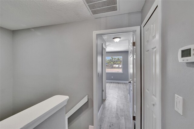 6601 121st Ave Unit I, Largo, FL 33773 - hallway with a textured ceiling and light wood-style flooring