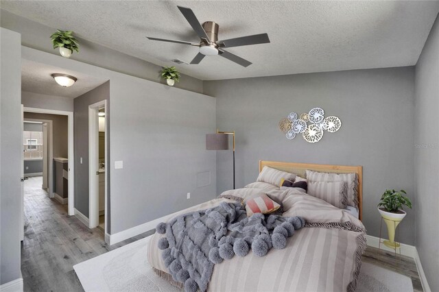 6601 121st Ave Unit I, Largo, FL 33773 - bedroom featuring light wood-style floors, a textured ceiling, and a ceiling fan