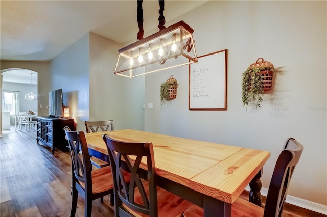 6648 Castle Green Pl, Zephyrhills, FL 33541 - dining area with arched walkways, wood finished floors, and a chandelier