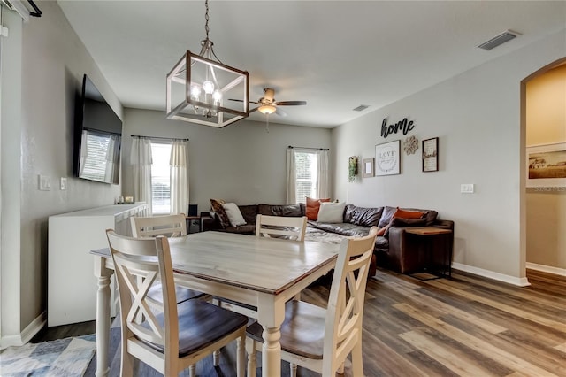 6648 Castle Green Pl, Zephyrhills, FL 33541 - dining room with arched walkways, light wood-style floors, a ceiling fan, and a chandelier