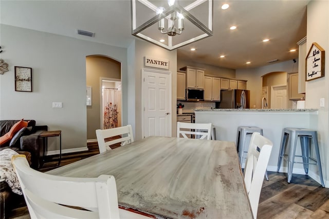 6648 Castle Green Pl, Zephyrhills, FL 33541 - dining space featuring arched walkways, recessed lighting, dark wood-style flooring, and a chandelier
