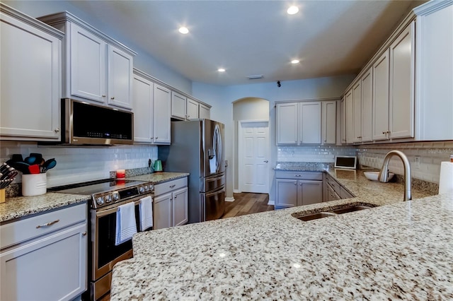 6648 Castle Green Pl, Zephyrhills, FL 33541 - kitchen with appliances with stainless steel finishes, tasteful backsplash, light stone countertops, recessed lighting, and arched walkways