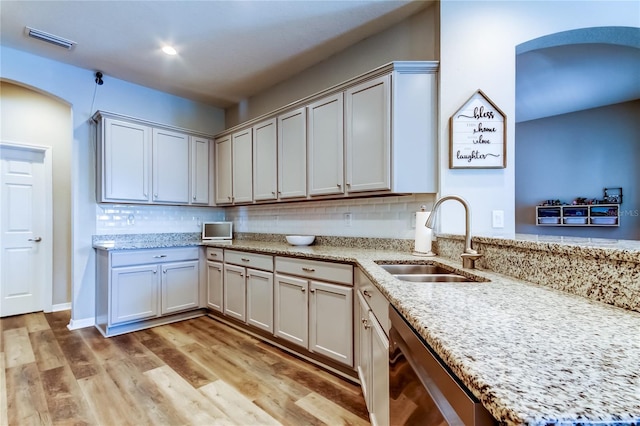 6648 Castle Green Pl, Zephyrhills, FL 33541 - kitchen with dishwasher, light wood-type flooring, tasteful backsplash, and light stone counters