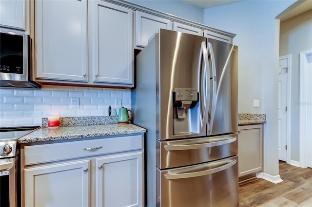 6648 Castle Green Pl, Zephyrhills, FL 33541 - kitchen featuring appliances with stainless steel finishes, backsplash, light wood finished floors, and light stone countertops