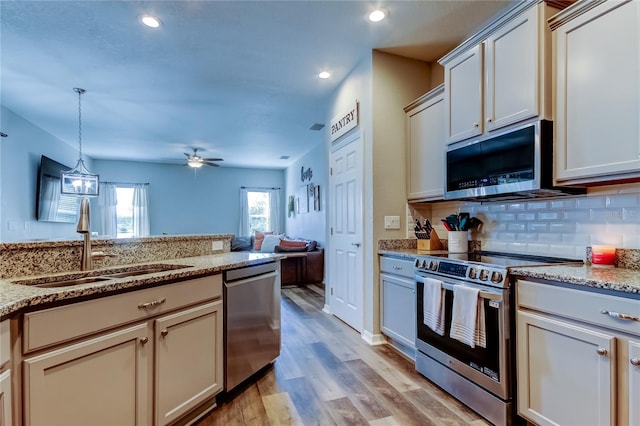 6648 Castle Green Pl, Zephyrhills, FL 33541 - kitchen with appliances with stainless steel finishes, light wood-style flooring, backsplash, a ceiling fan, and light stone countertops