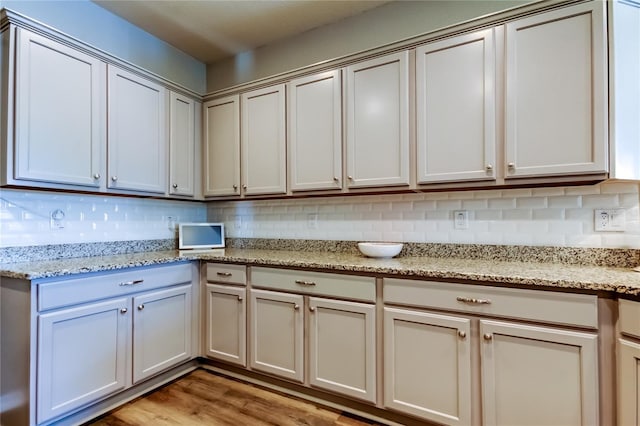 6648 Castle Green Pl, Zephyrhills, FL 33541 - kitchen with backsplash, light wood-style flooring, and light stone countertops