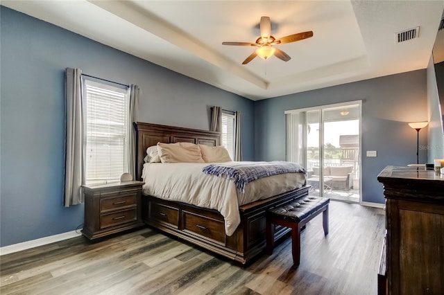 6648 Castle Green Pl, Zephyrhills, FL 33541 - bedroom with a tray ceiling, access to exterior, wood finished floors, and a ceiling fan