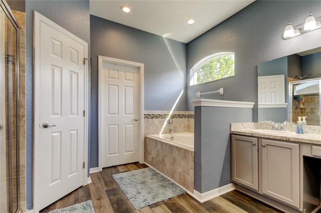 6648 Castle Green Pl, Zephyrhills, FL 33541 - bathroom featuring vanity, a shower stall, a garden tub, and wood finished floors