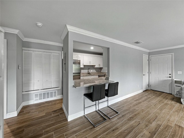 13285 Arbor Pointe Cir Unit 202, Tampa, FL 33617 - kitchen with dark wood finished floors, white cabinetry, ornamental molding, freestanding refrigerator, and light stone counters