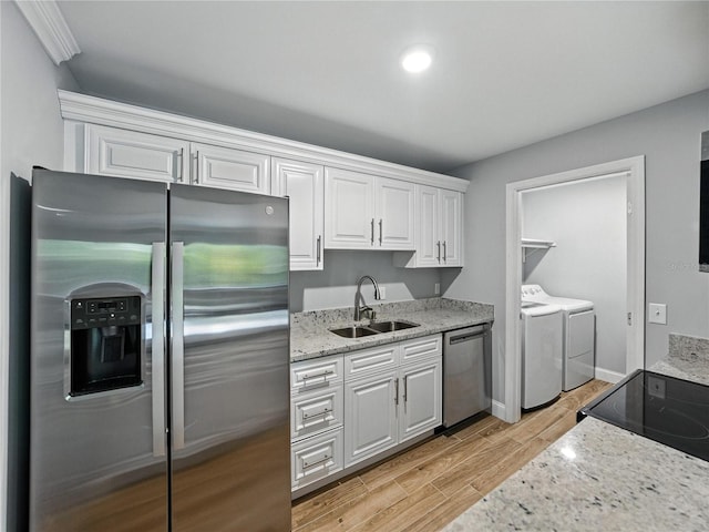 13285 Arbor Pointe Cir Unit 202, Tampa, FL 33617 - kitchen featuring appliances with stainless steel finishes, washing machine and dryer, white cabinetry, light wood-style flooring, and light stone countertops