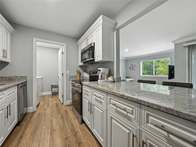 13285 Arbor Pointe Cir Unit 202, Tampa, FL 33617 - kitchen featuring stainless steel appliances, washer and dryer, white cabinetry, light wood finished floors, and light stone countertops