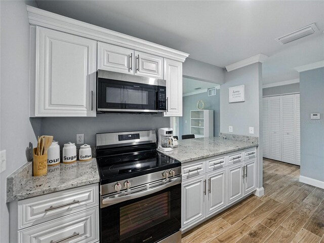 13285 Arbor Pointe Cir Unit 202, Tampa, FL 33617 - kitchen with appliances with stainless steel finishes, crown molding, white cabinets, and light wood finished floors