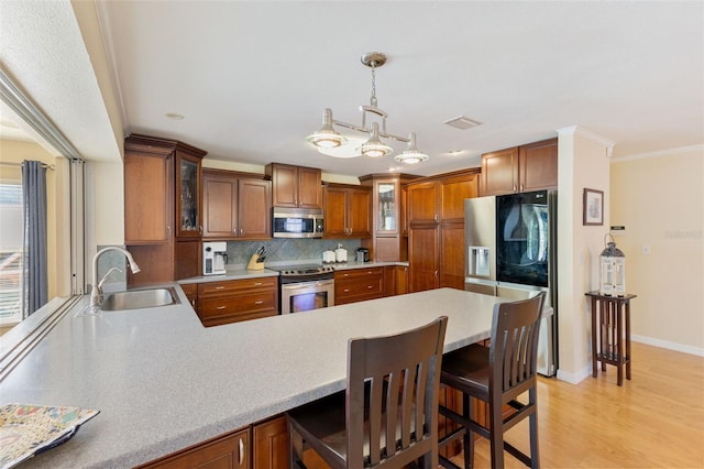 218 N Bay Hills Blvd, Safety Harbor, FL 34695 - kitchen with appliances with stainless steel finishes, brown cabinetry, a peninsula, tasteful backsplash, and light countertops