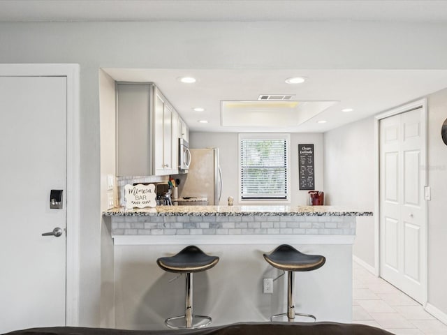 214 Meadow Ln Unit 214, Oldsmar, FL 34677 - kitchen with stainless steel microwave, freestanding refrigerator, a breakfast bar, a peninsula, and light tile patterned floors