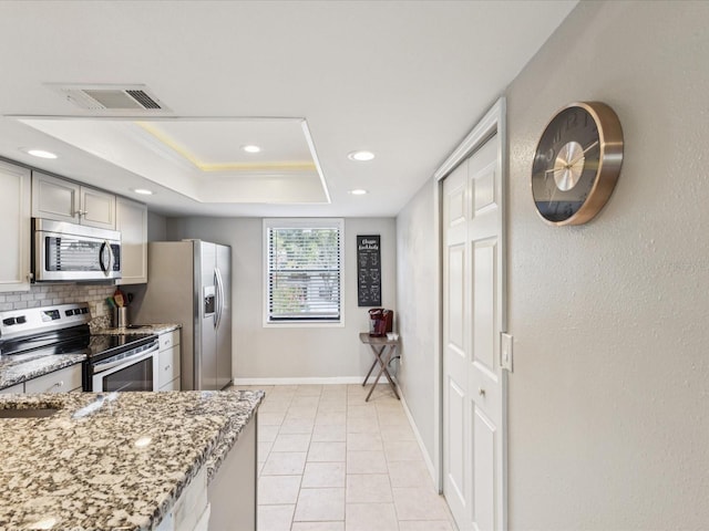214 Meadow Ln Unit 214, Oldsmar, FL 34677 - kitchen featuring appliances with stainless steel finishes, recessed lighting, light stone counters, tasteful backsplash, and a tray ceiling